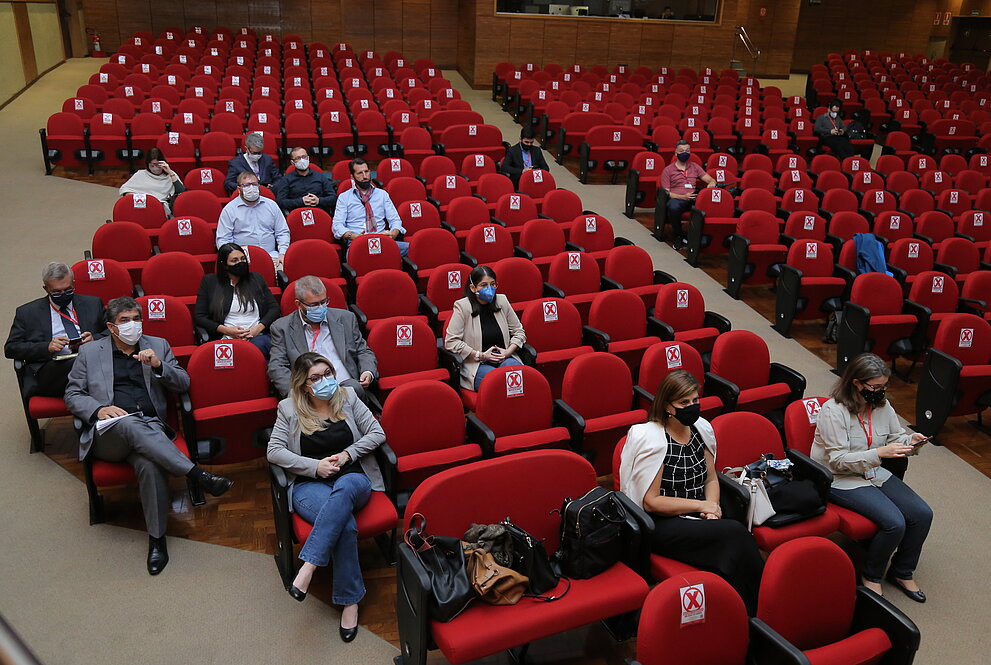 pessoas assentadas em cadeiras vermelhas em auditório