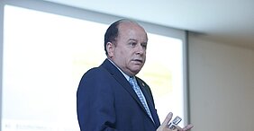 reitor da Universidade Presbiteriana Mackenzie aparece em frente ao data show, durante sua apresentação da palestra