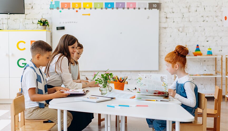 Crianças maiores sentadas de um lado da mesa e uma criança mais nova sentada do outro lado da mesa