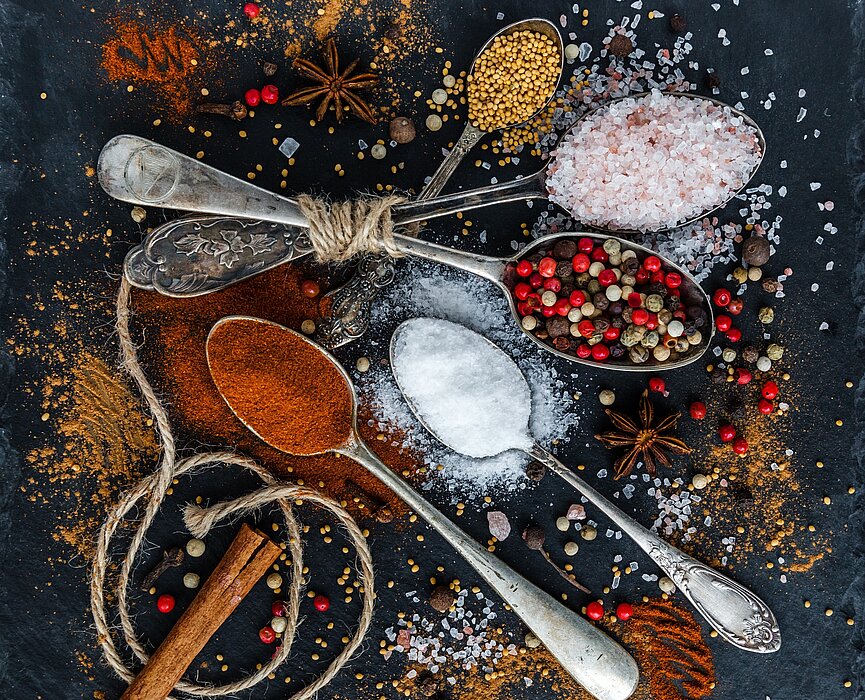 alimentos e temperos espalhados em cima de uma mesa e sobre colheres