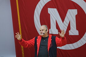 Homem alto discurso com bandeira do Mackenzie ao fundo
