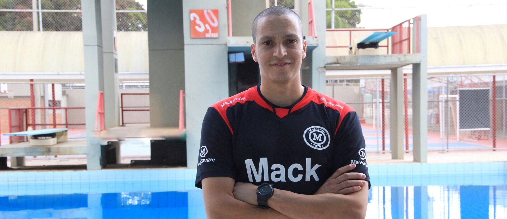 Atleta César Castro parado em frente a piscina do Colégio Mackenzie Brasília