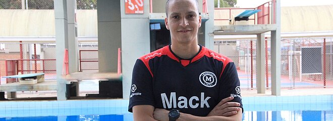 Atleta César Castro parado em frente a piscina do Colégio Mackenzie Brasília