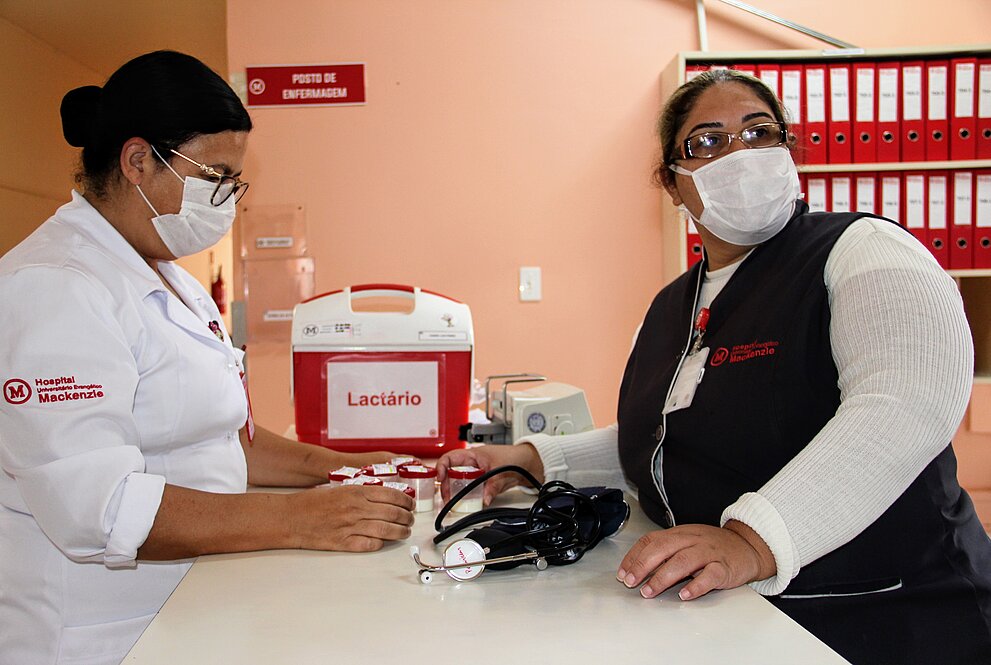 duas mulheres de máscaras e aventais do hospital trabalhando
