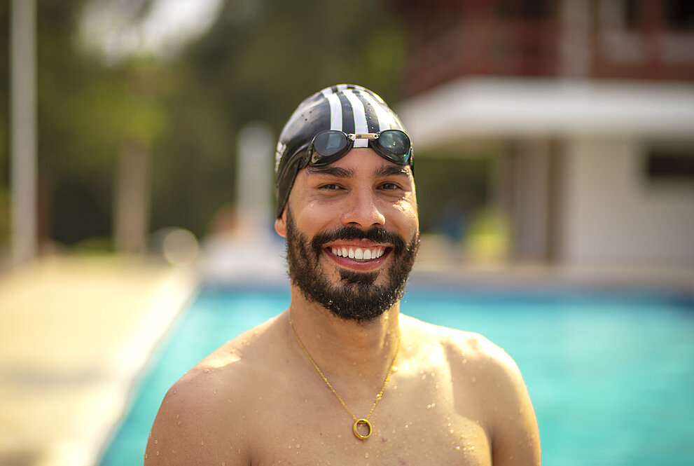 homem sorri de frente pra piscina