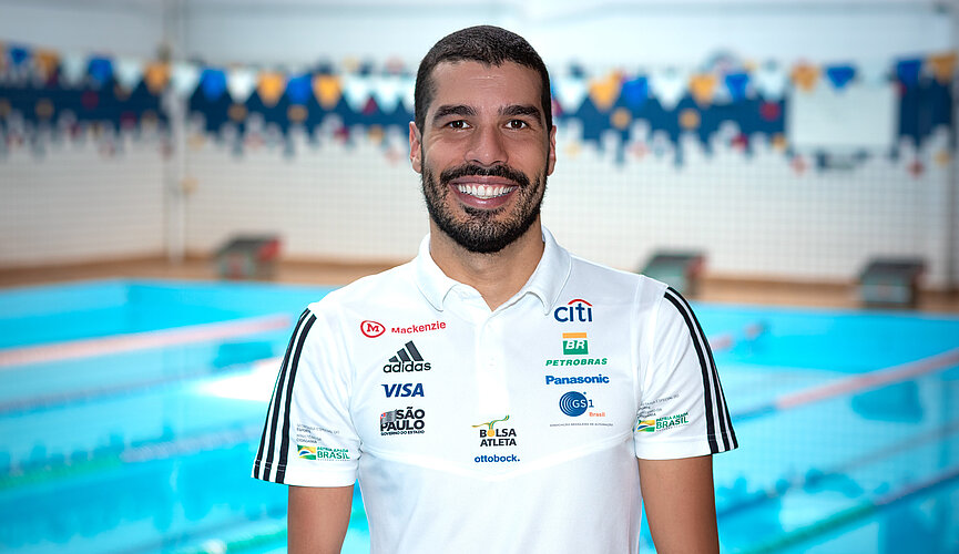 Homem sorridente parado em frente a uma piscina