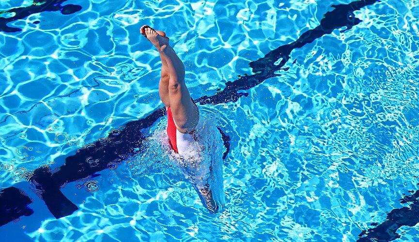 Atleta treinando nado artístico na piscina 