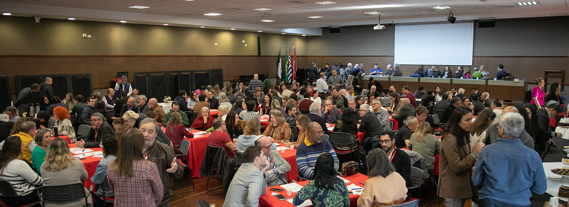 Imagem tirada do "XI Fórum de Aprendizagem Transformadora" e nela contem um auditório cheio pessoas sentadas debatendo.