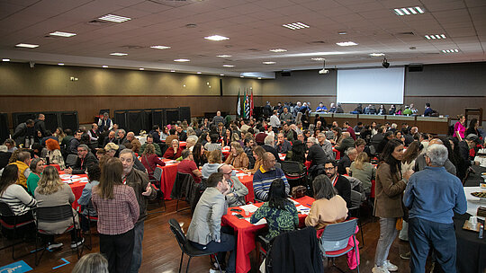 Imagem tirada do "XI Fórum de Aprendizagem Transformadora" e nela contem um auditório cheio pessoas sentadas debatendo.