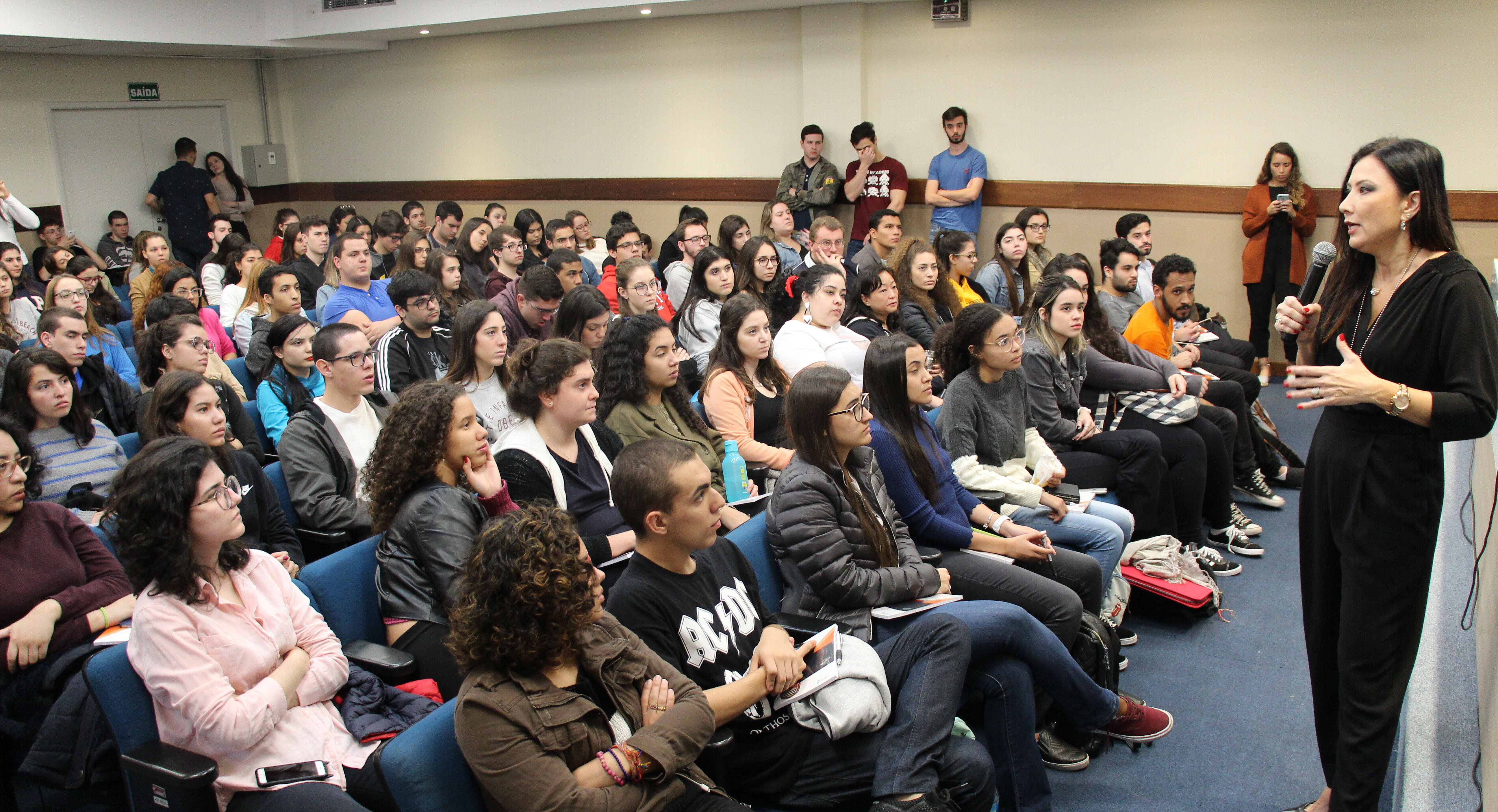 Palestrante à frente de plateia cheia