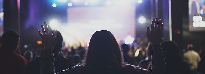 mulher de costas de braços levantados em uma plateia de um show