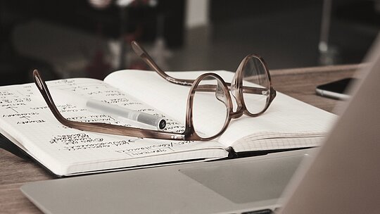 óculos e caderno em cima de uma mesa