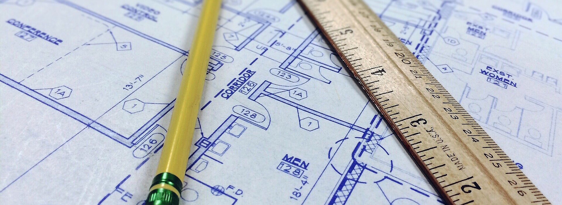 Imagem com um projeto de arquitetura desenhado no papel e junto com um lápis e uma régua